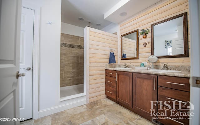 bathroom with vanity, tiled shower, and wooden walls