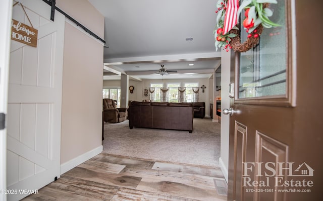 foyer with hardwood / wood-style flooring, a barn door, ceiling fan, and beamed ceiling