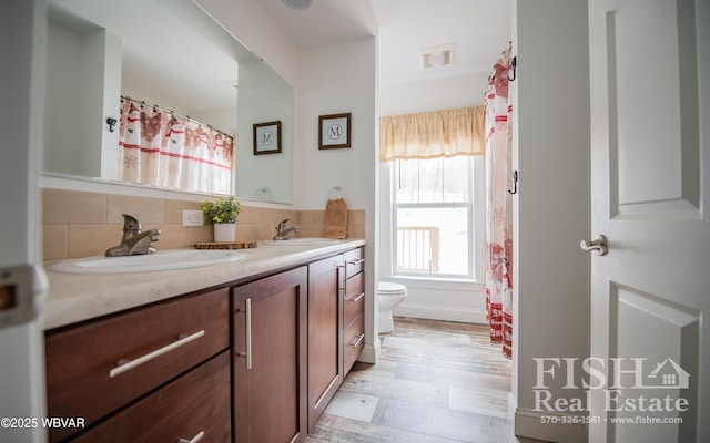 bathroom featuring vanity, hardwood / wood-style floors, tasteful backsplash, and toilet