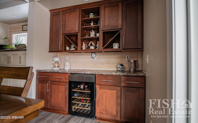 bar with light hardwood / wood-style floors, light stone countertops, and beverage cooler