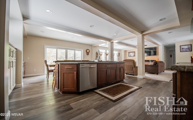 kitchen featuring a center island with sink, dark wood-type flooring, stainless steel dishwasher, and beamed ceiling