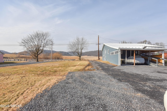 view of yard featuring an attached carport, an outdoor structure, driveway, and a pole building