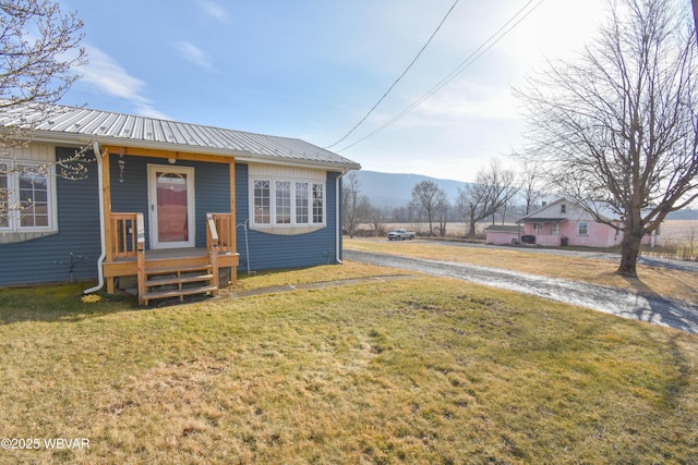 bungalow featuring metal roof, a mountain view, and a front yard