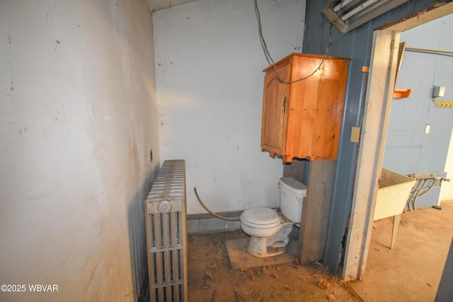 bathroom featuring toilet, concrete floors, and radiator heating unit