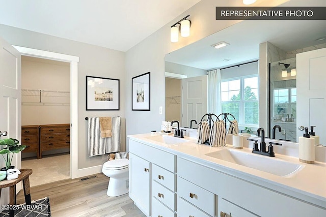 2287 Warrensville Rd, Montoursville, PA 17754 - full bathroom with a shower stall, wood finished floors, double vanity, a walk in closet, and toilet