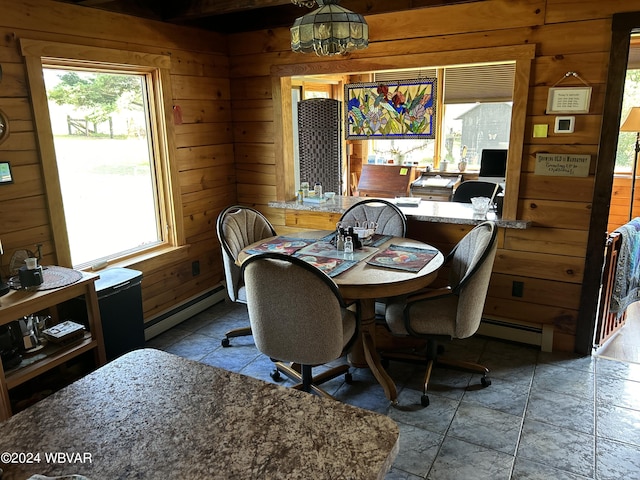 dining room featuring wooden walls, plenty of natural light, and a baseboard radiator