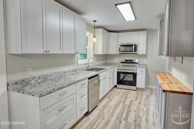 294 Park Ave, Lock Haven, PA 17745 - kitchen featuring stainless steel appliances, a sink, light wood finished floors, white cabinets, and butcher block countertops