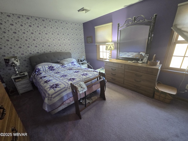 bedroom featuring wallpapered walls, multiple windows, light colored carpet, and visible vents