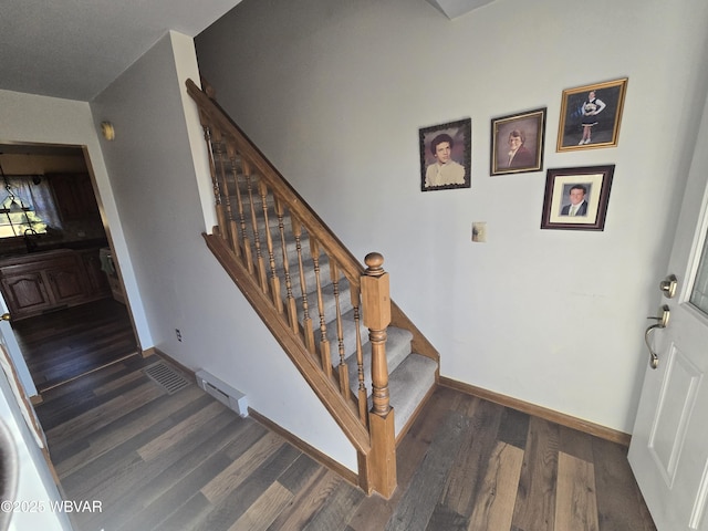 staircase with visible vents, wood finished floors, and baseboards