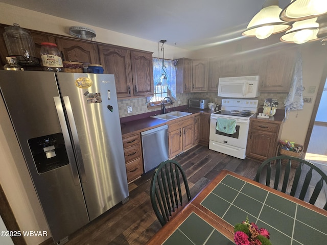 kitchen with dark wood-style floors, backsplash, appliances with stainless steel finishes, and a sink