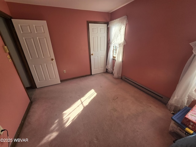 unfurnished bedroom with light colored carpet, a baseboard heating unit, and baseboards