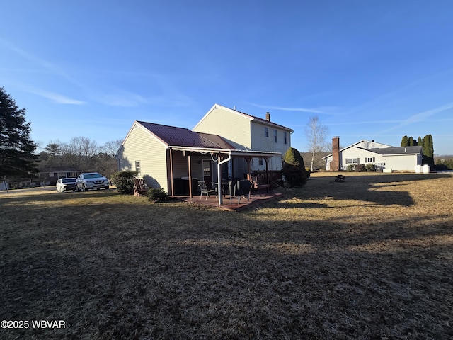 rear view of property featuring metal roof, a yard, a chimney, and a patio area