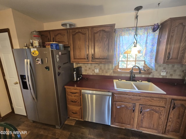 kitchen with a sink, dark countertops, backsplash, and stainless steel appliances