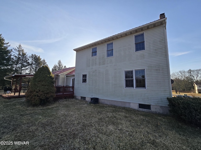 rear view of house featuring a lawn, a chimney, and a deck