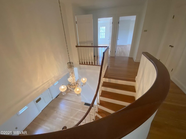 stairs featuring a chandelier and wood finished floors