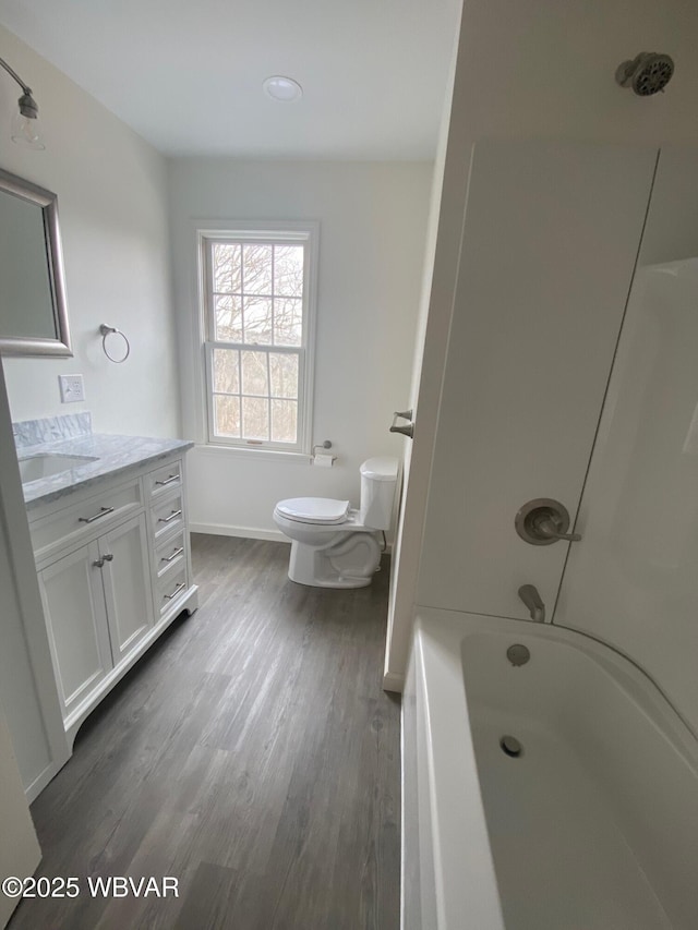 bathroom with baseboards, vanity, toilet, and wood finished floors