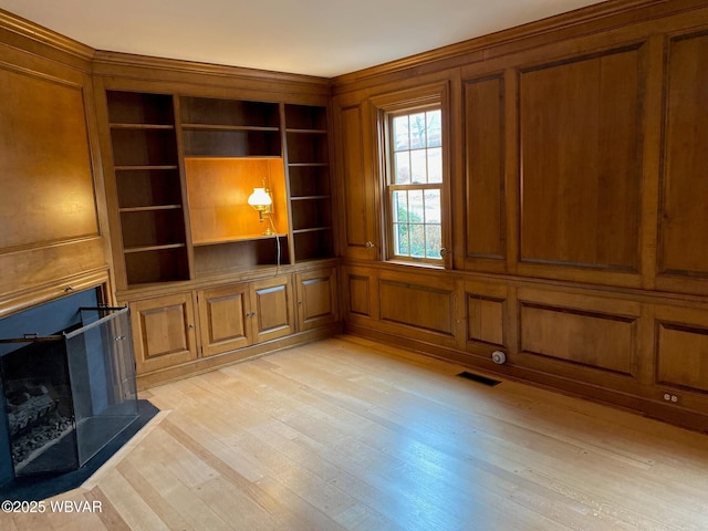 unfurnished living room with light wood-style floors, a fireplace, and visible vents