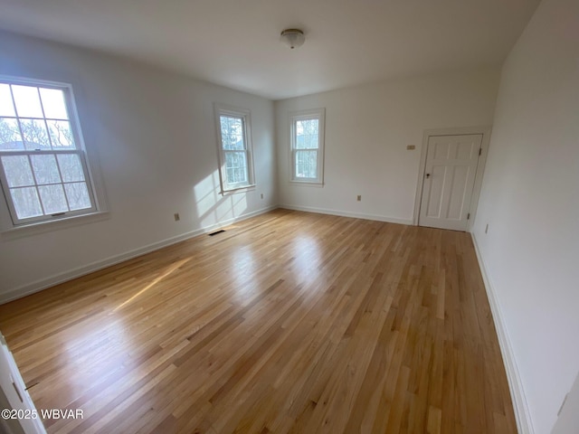 unfurnished room featuring light wood finished floors, baseboards, visible vents, and a wealth of natural light