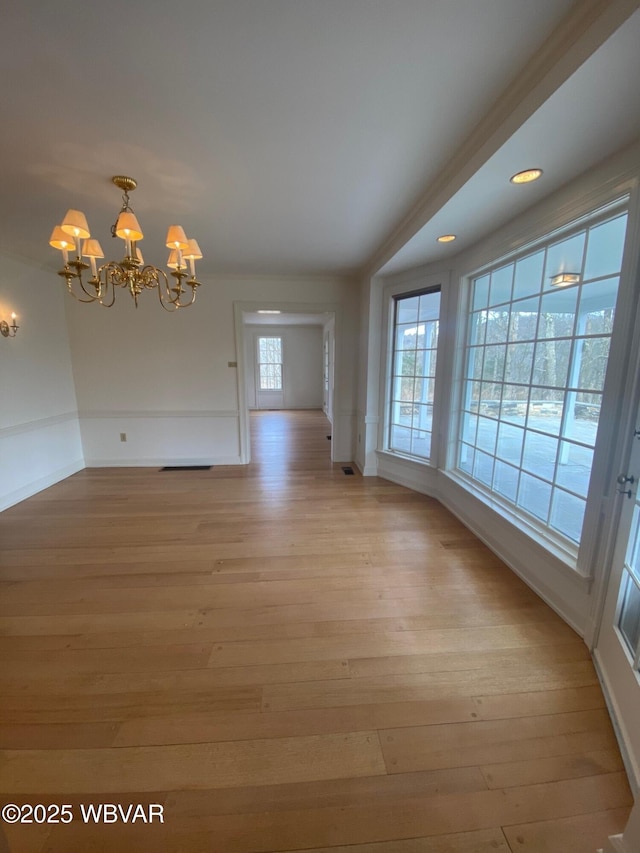 unfurnished dining area featuring a chandelier, light wood-style flooring, and baseboards