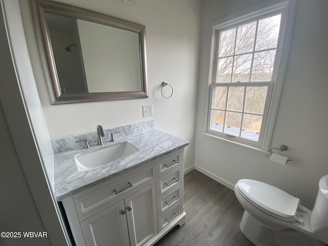 bathroom with wood finished floors, vanity, toilet, and baseboards