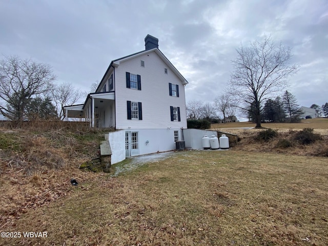 back of property with a chimney, french doors, central AC, and a yard