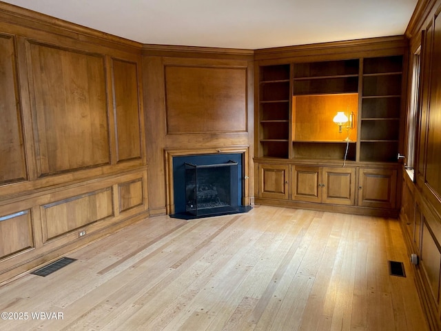 unfurnished living room featuring light wood-type flooring, a fireplace, and visible vents