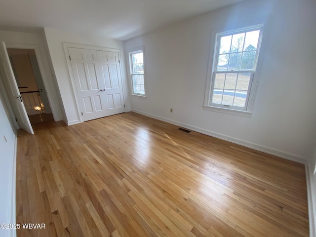 unfurnished bedroom with light wood-style flooring, a closet, visible vents, and baseboards