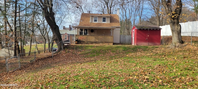 rear view of property featuring a lawn and a storage shed