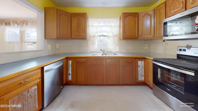 kitchen with tasteful backsplash, sink, and appliances with stainless steel finishes