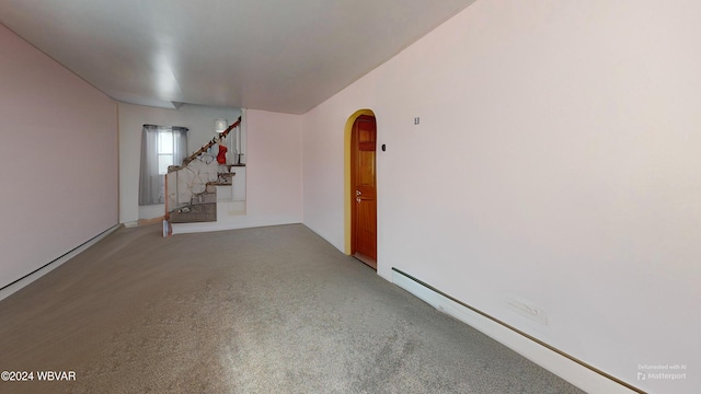 carpeted empty room featuring a baseboard heating unit