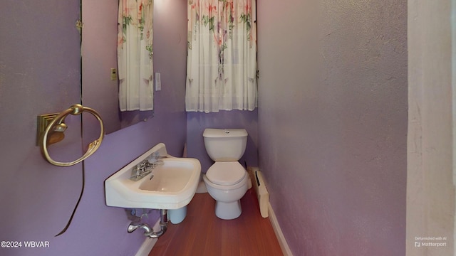 bathroom with hardwood / wood-style floors, toilet, baseboard heating, and sink