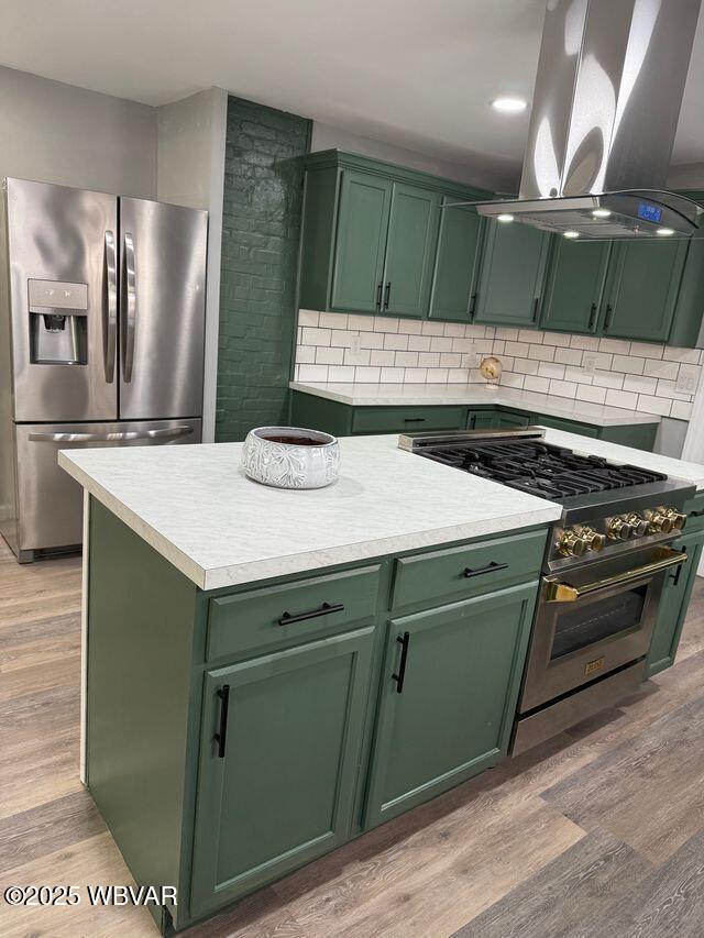 kitchen featuring island exhaust hood, light hardwood / wood-style floors, stainless steel appliances, and green cabinetry