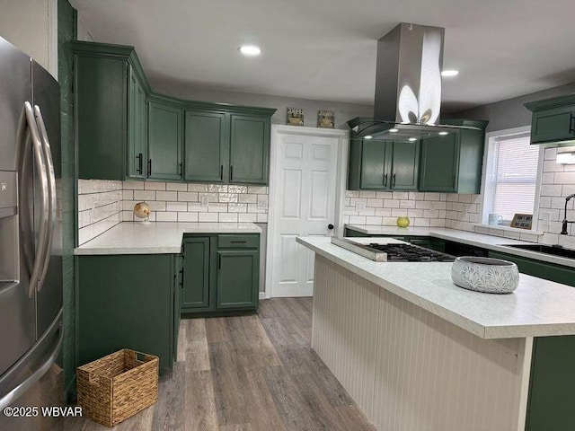 kitchen with dark hardwood / wood-style floors, sink, green cabinetry, stainless steel appliances, and island range hood