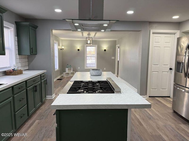 kitchen with backsplash, a kitchen island, wood-type flooring, island exhaust hood, and stainless steel appliances