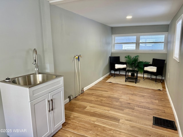 living area featuring light wood-type flooring, plenty of natural light, and sink