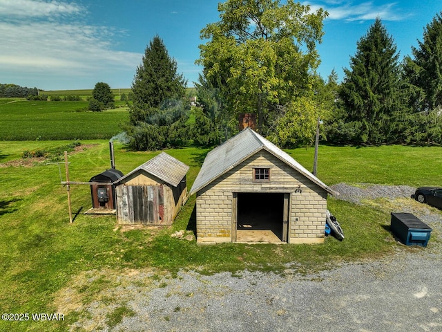 view of outbuilding with a rural view and a lawn