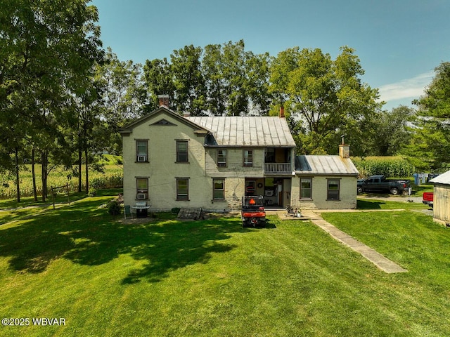 rear view of property featuring a balcony and a lawn