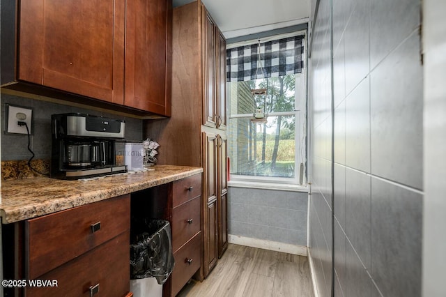 kitchen with light stone counters, tile walls, and light wood-type flooring