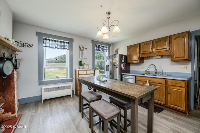 kitchen with sink, hanging light fixtures, light hardwood / wood-style flooring, radiator, and stainless steel appliances