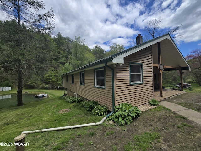 view of home's exterior with a chimney and a yard