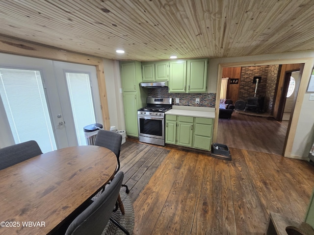 kitchen with green cabinets, gas stove, under cabinet range hood, a wood stove, and dark wood finished floors