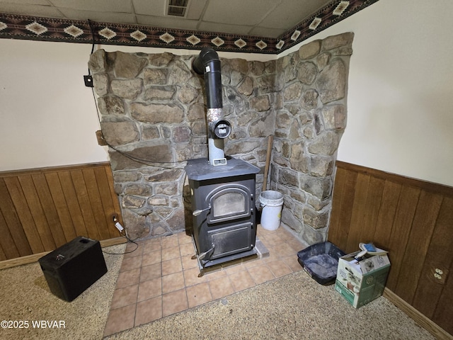 detailed view of a wainscoted wall, a wood stove, and wooden walls