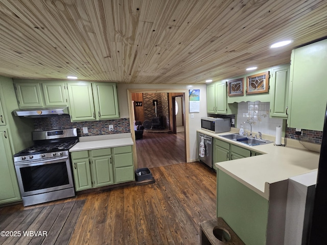kitchen featuring green cabinets, appliances with stainless steel finishes, a sink, light countertops, and under cabinet range hood
