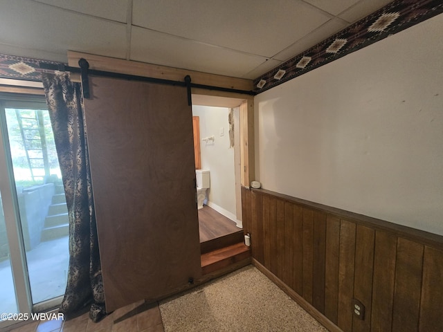 hallway with a wainscoted wall, a barn door, and wooden walls