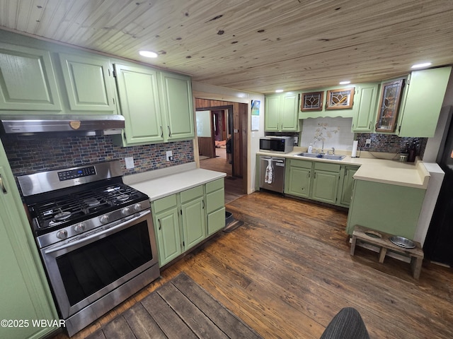 kitchen featuring green cabinetry, stainless steel appliances, under cabinet range hood, a sink, and tasteful backsplash