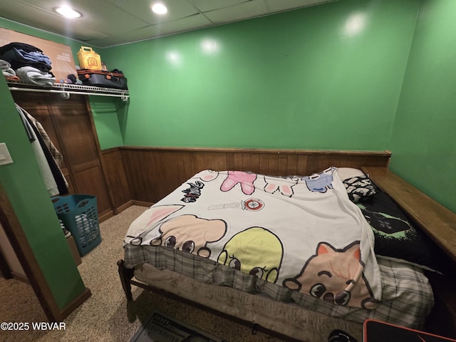 carpeted bedroom featuring a wainscoted wall and wood walls