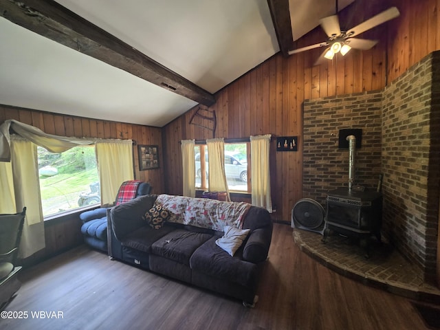 living room featuring healthy amount of natural light, wood finished floors, a wood stove, wood walls, and ceiling fan