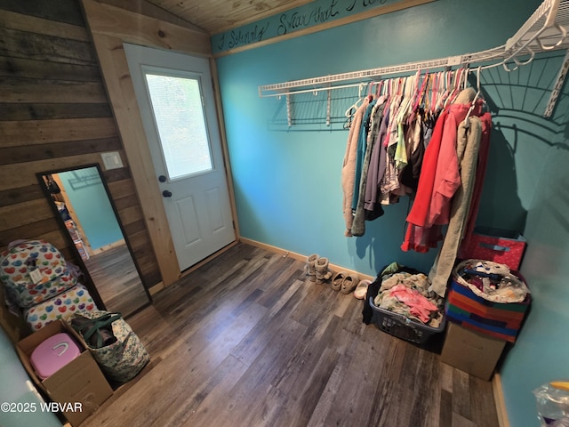 interior space with wood finished floors, lofted ceiling, baseboards, and wooden walls