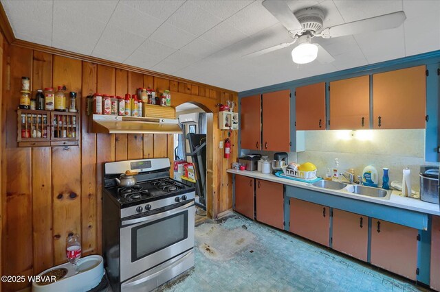 522 S Main St, Jersey Shore, PA 17740 - kitchen featuring gas stove, arched walkways, wood walls, and under cabinet range hood