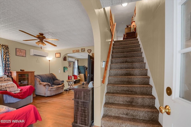 522 S Main St, Jersey Shore, PA 17740 - stairway featuring wood finished floors, a wall unit AC, a ceiling fan, and arched walkways